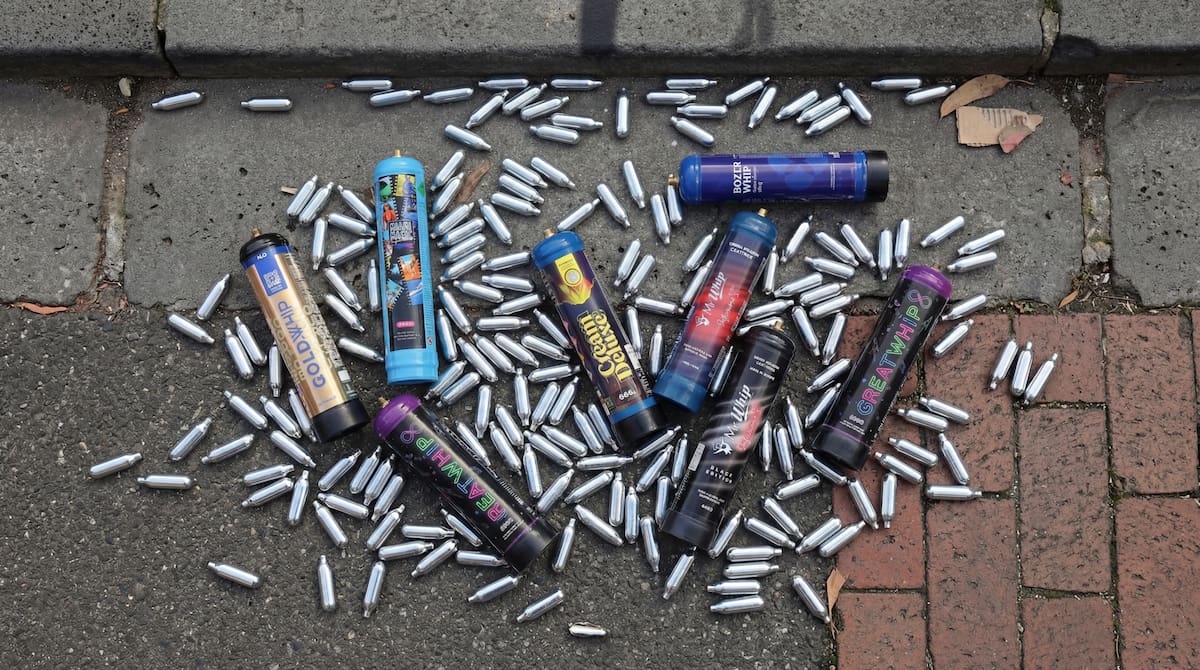 Nitrous oxide cream charger canisters on a white surface requiring legal disposal in Melbourne